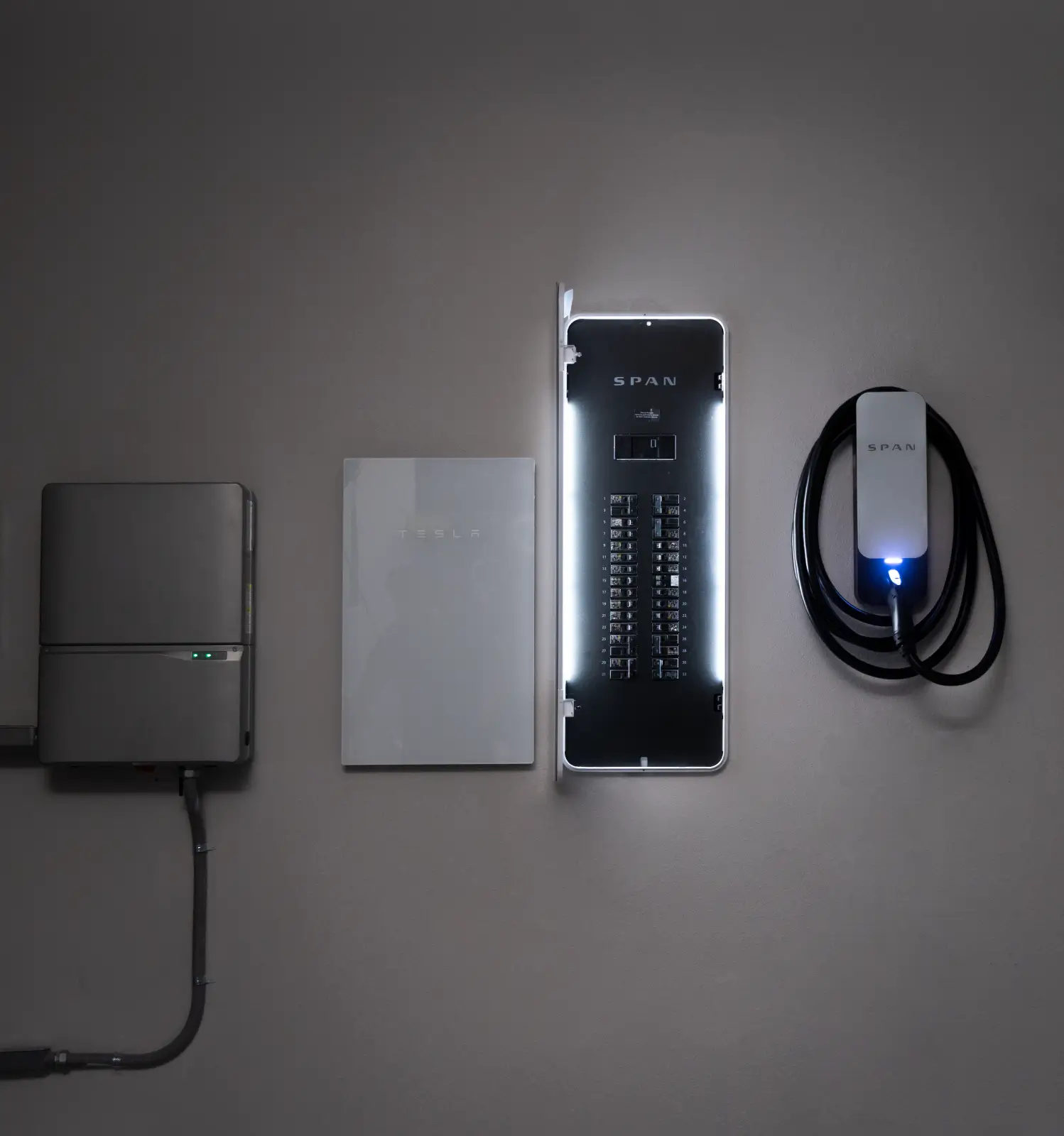 Three wall-mounted electrical devices, including a Tesla Powerwall, smart electrical panels with lights, and a Span EV charger with a coiled cable.