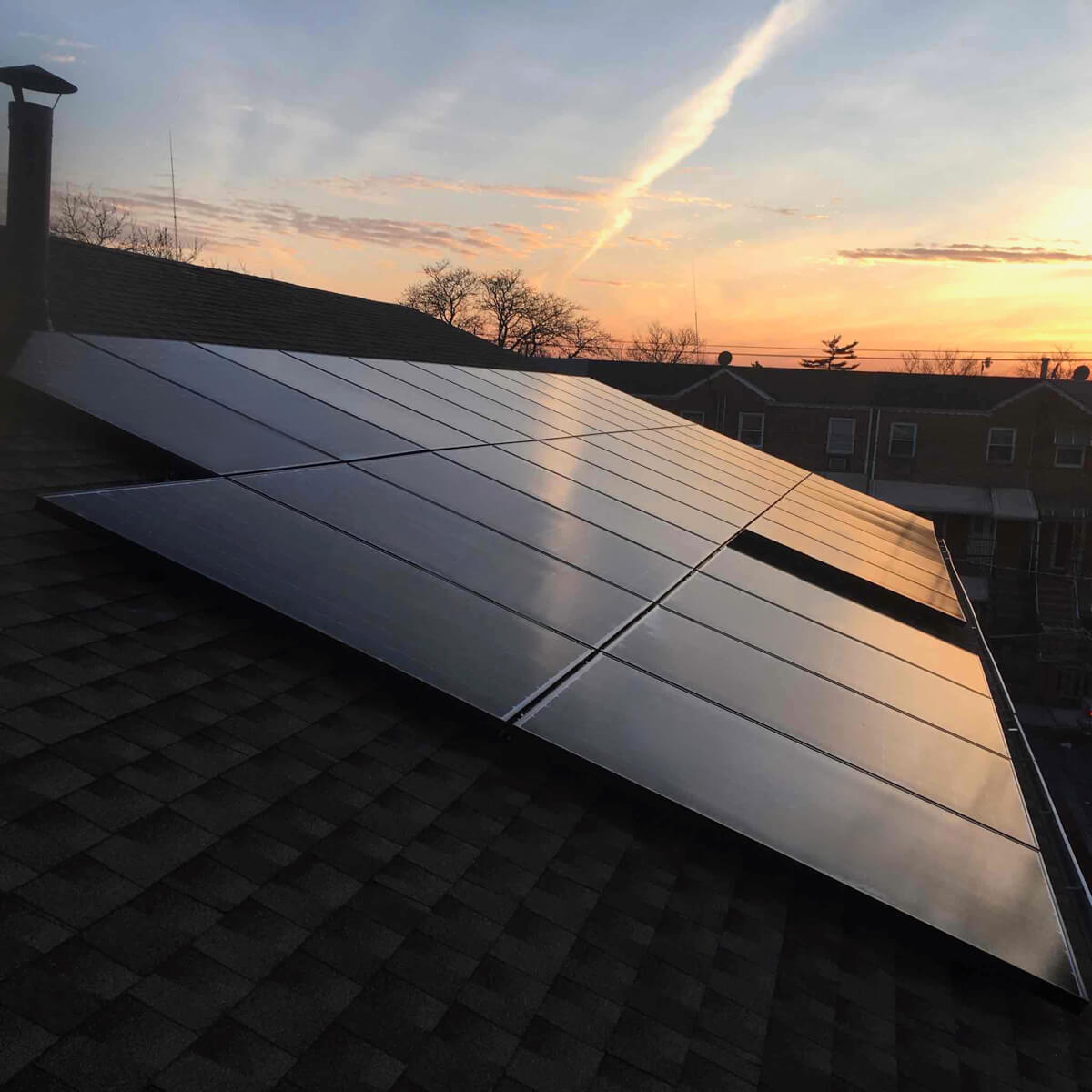 The sunset reflecting beautifully off solar panels installed on a home’s roof.