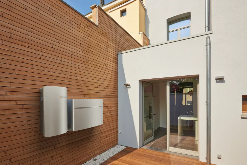 A wooden exterior wall with Enphase battery units attached.