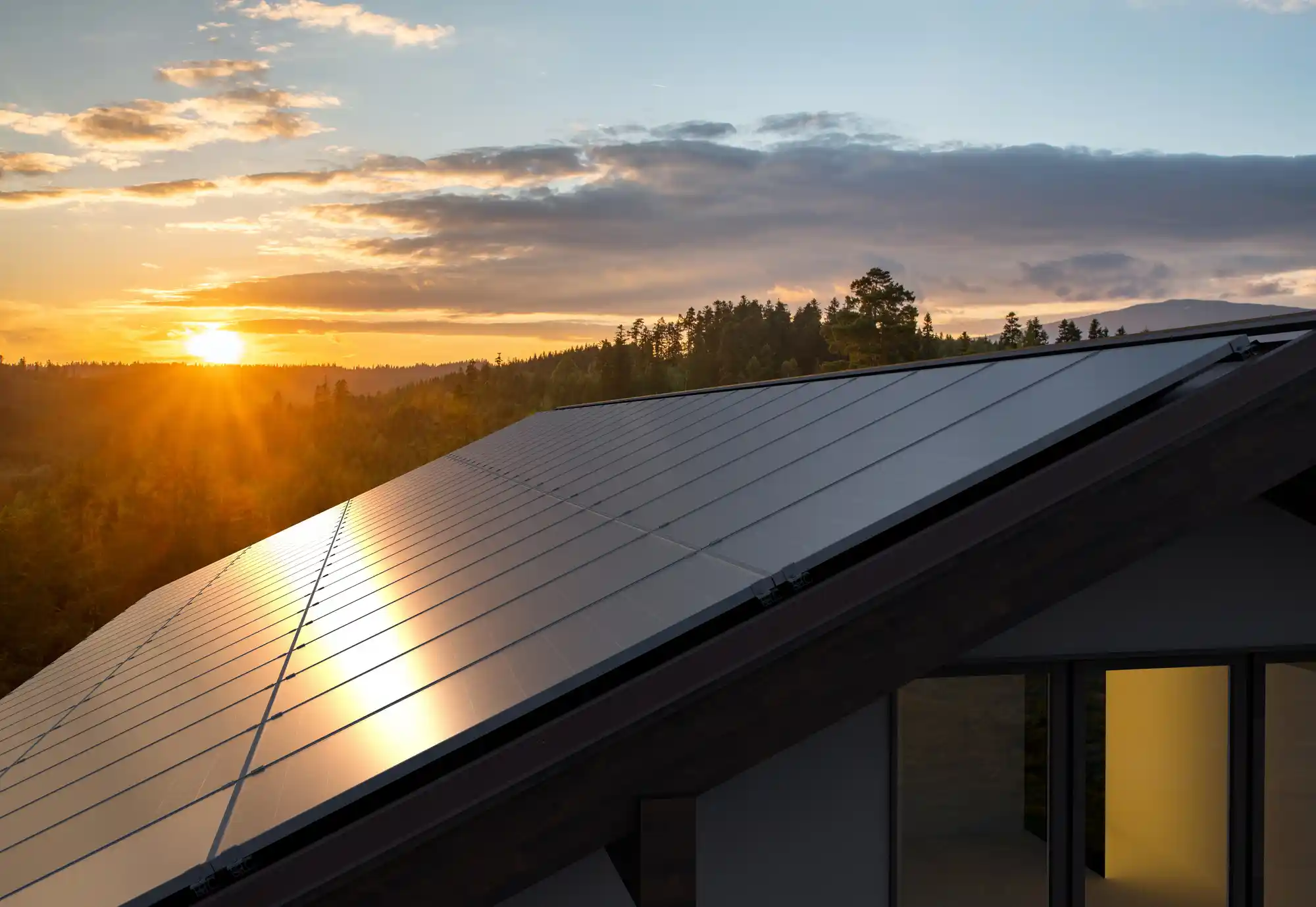 Solar panels on a house roof, expertly installed by solar experts, reflect the setting sun.